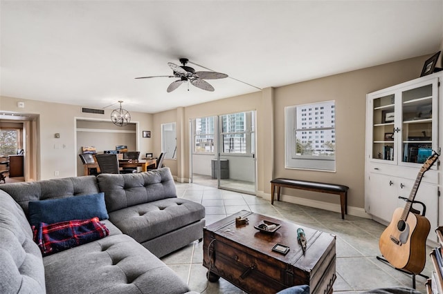 living room featuring light tile patterned flooring, plenty of natural light, ceiling fan with notable chandelier, and visible vents