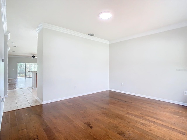 unfurnished room with visible vents, a ceiling fan, wood finished floors, crown molding, and baseboards