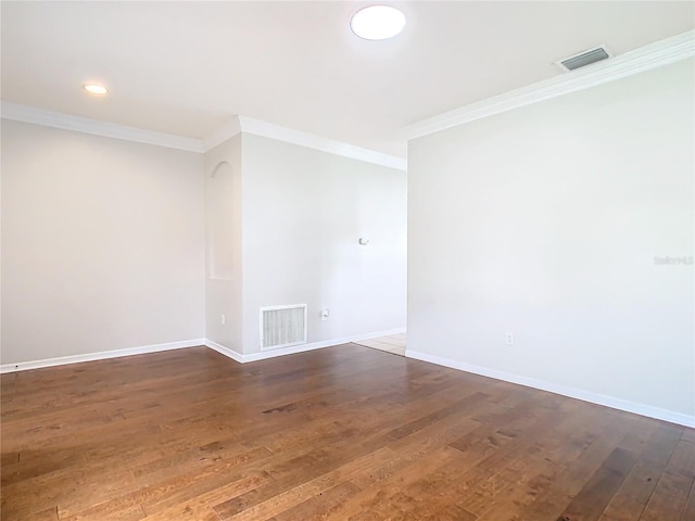 unfurnished room with dark wood finished floors, visible vents, crown molding, and baseboards