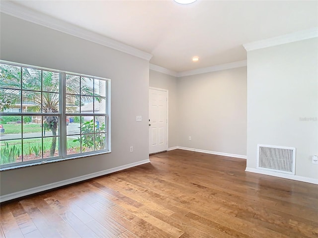 unfurnished room with visible vents, baseboards, wood finished floors, and ornamental molding