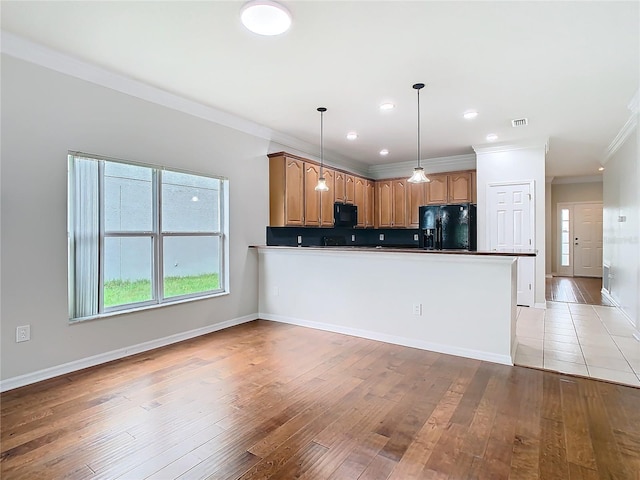 kitchen featuring backsplash, ornamental molding, light wood-style flooring, a peninsula, and black appliances