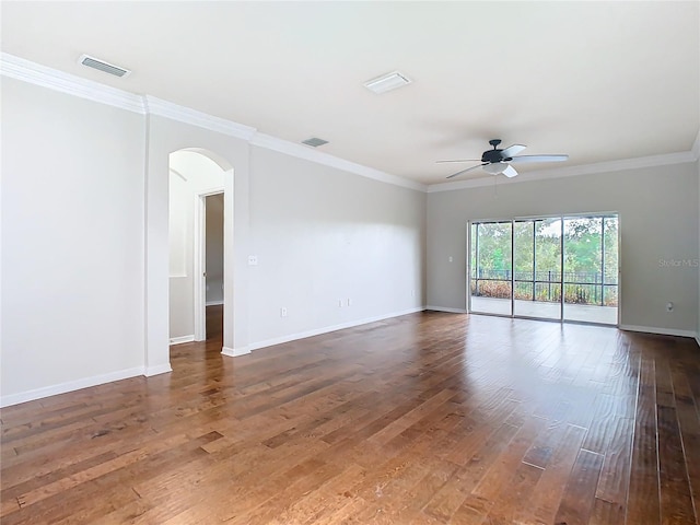 empty room featuring visible vents, arched walkways, crown molding, and hardwood / wood-style flooring