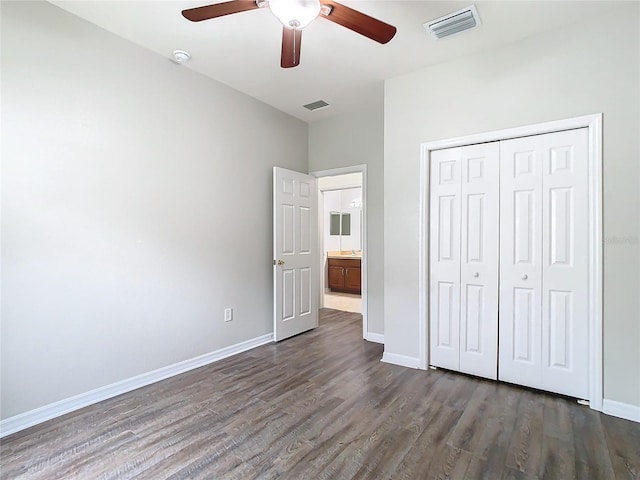 unfurnished bedroom with dark wood-style floors, visible vents, a closet, and baseboards