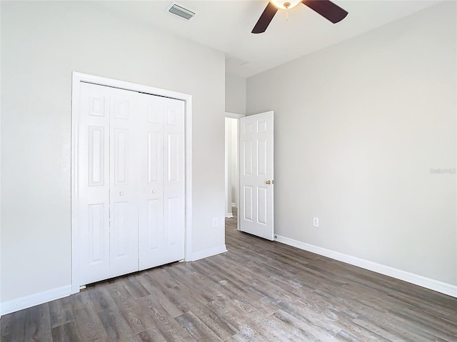 unfurnished bedroom featuring visible vents, a ceiling fan, wood finished floors, a closet, and baseboards