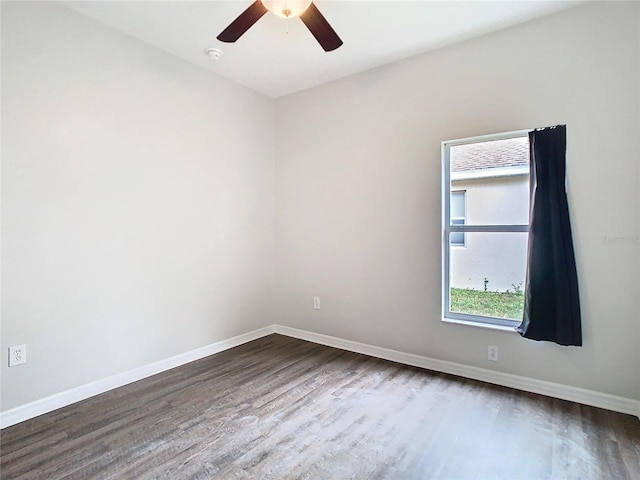 unfurnished room featuring a ceiling fan, dark wood-type flooring, and baseboards