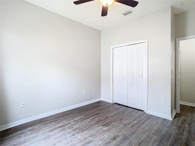 unfurnished bedroom with visible vents, baseboards, a closet, and dark wood finished floors