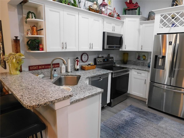 kitchen featuring a peninsula, white cabinets, appliances with stainless steel finishes, and a sink