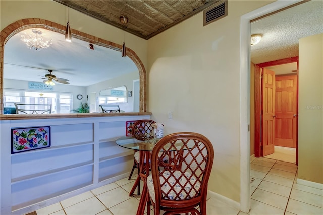 dining area with visible vents, baseboards, light tile patterned floors, arched walkways, and a ceiling fan