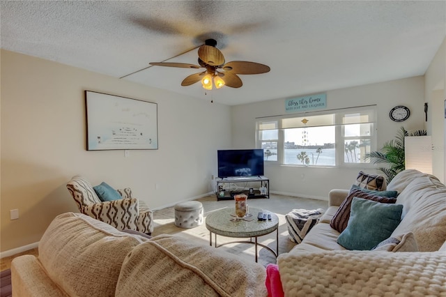 carpeted living room featuring ceiling fan, a textured ceiling, and baseboards