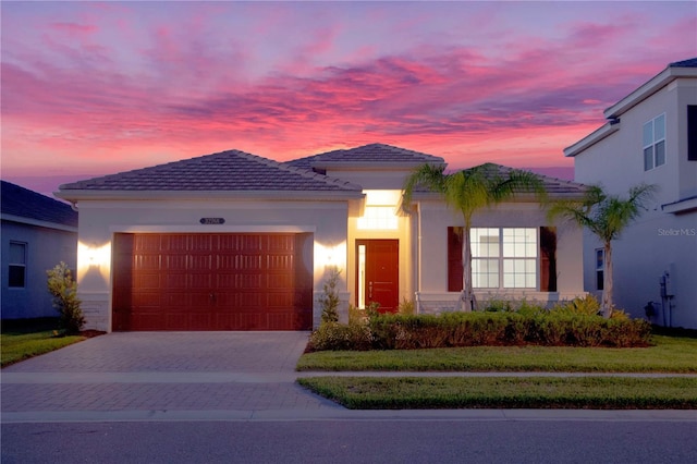 mediterranean / spanish-style house with stucco siding, a tiled roof, driveway, and a garage