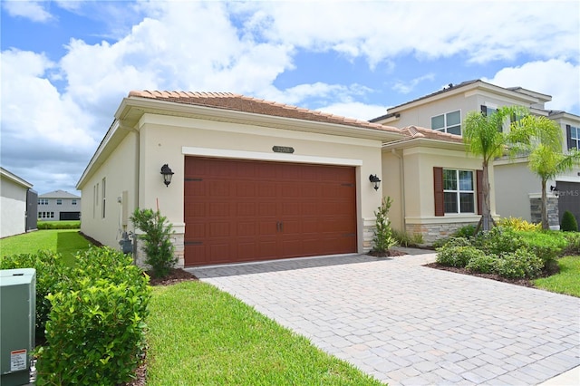 view of front of home featuring stucco siding, decorative driveway, stone siding, a garage, and a tiled roof