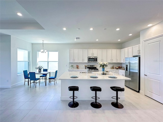 kitchen with a kitchen bar, white cabinetry, and stainless steel appliances