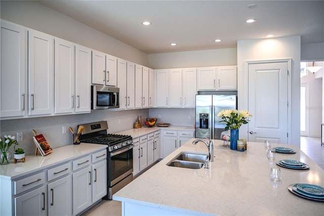 kitchen with a sink, recessed lighting, stainless steel appliances, white cabinets, and light stone countertops