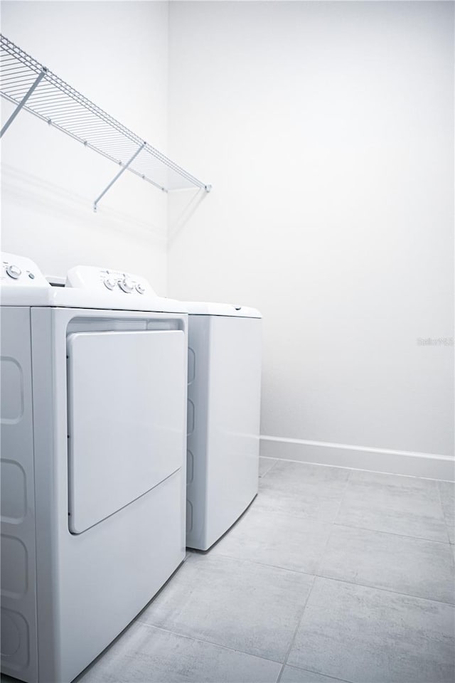 clothes washing area with laundry area, washer and dryer, and baseboards