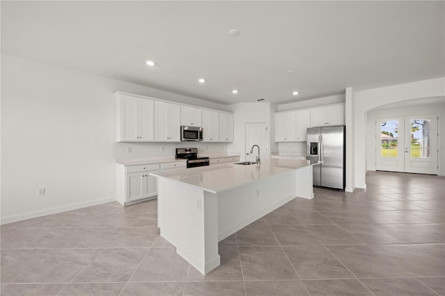 kitchen featuring an island with sink, a sink, french doors, appliances with stainless steel finishes, and white cabinets