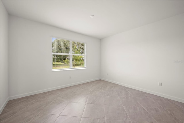 unfurnished room with light tile patterned floors and baseboards