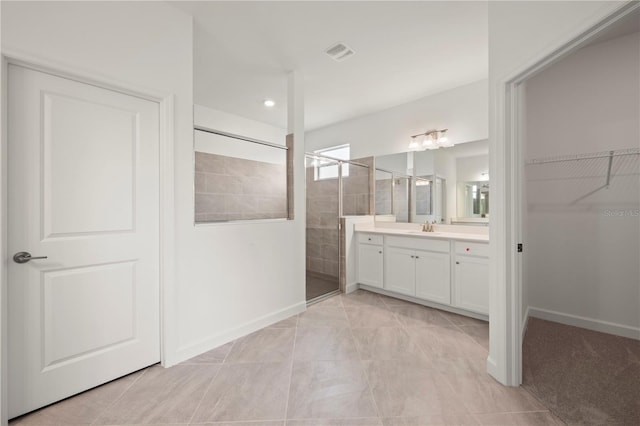 full bathroom with vanity, baseboards, visible vents, a spacious closet, and walk in shower