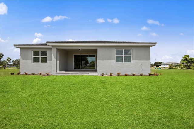 back of property with a patio area, a lawn, and stucco siding