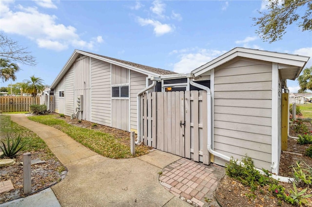 view of outbuilding featuring fence and a gate