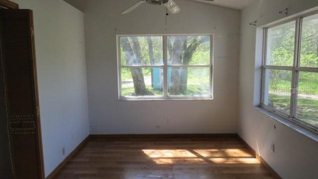 unfurnished room with a ceiling fan, vaulted ceiling, wood finished floors, and baseboards