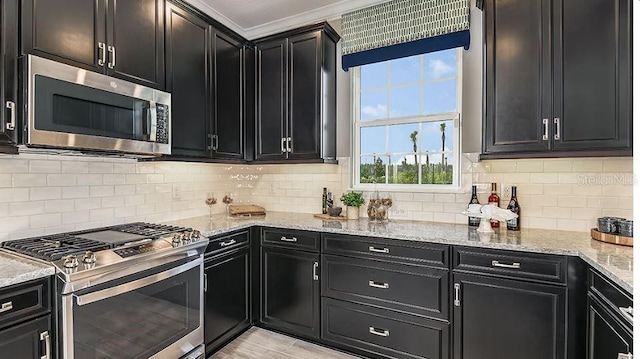 kitchen featuring tasteful backsplash, light stone countertops, dark cabinets, and stainless steel appliances