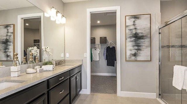 bathroom with baseboards, double vanity, a stall shower, a sink, and tile patterned flooring