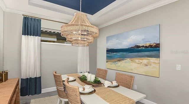 dining space featuring ornamental molding, a tray ceiling, wood finished floors, an inviting chandelier, and baseboards