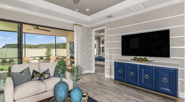 living room featuring visible vents, light wood-style flooring, a ceiling fan, and crown molding