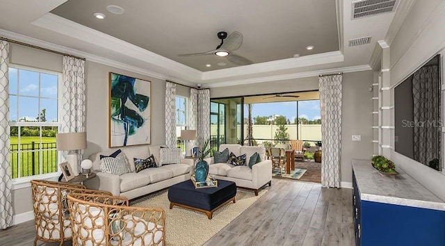 living room with a raised ceiling, ceiling fan, and wood finished floors