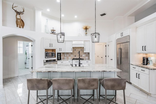 kitchen featuring arched walkways, visible vents, appliances with stainless steel finishes, and white cabinetry