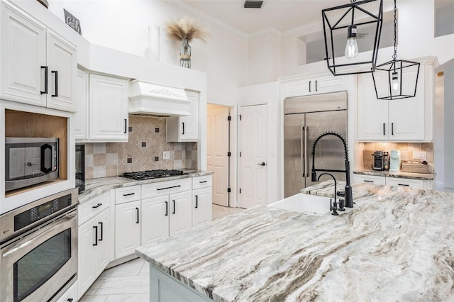 kitchen with stainless steel appliances, white cabinetry, ornamental molding, and custom range hood