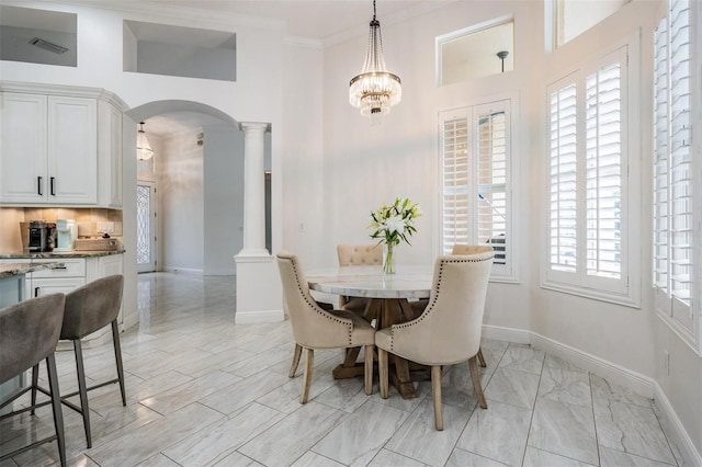 dining space with visible vents, crown molding, baseboards, decorative columns, and arched walkways