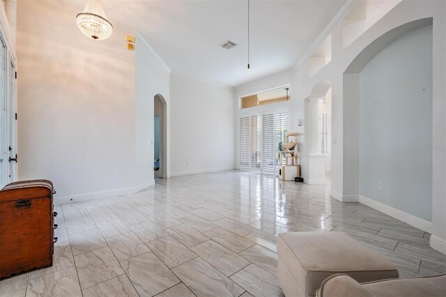 empty room featuring arched walkways, visible vents, crown molding, and baseboards