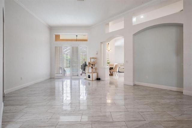 spare room featuring baseboards, arched walkways, and ornamental molding