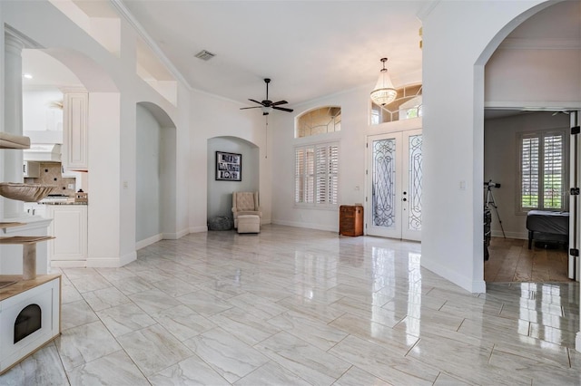 entrance foyer featuring visible vents, marble finish floor, arched walkways, crown molding, and baseboards