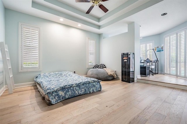 bedroom with recessed lighting, baseboards, a tray ceiling, and wood finished floors