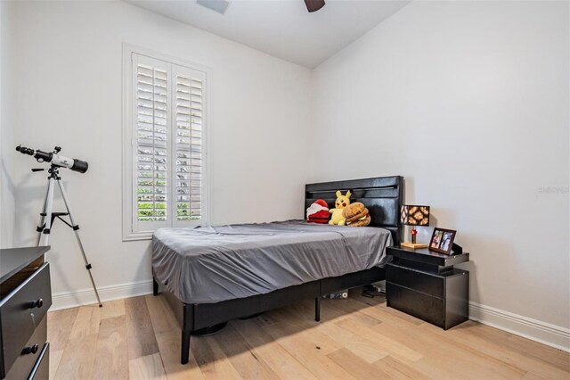 bedroom with light wood finished floors, a ceiling fan, and baseboards