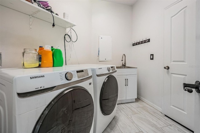 clothes washing area featuring a sink, cabinet space, baseboards, and washing machine and clothes dryer