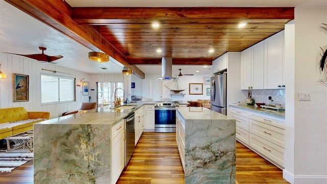 kitchen featuring light wood finished floors, island range hood, a large island, stainless steel appliances, and a sink