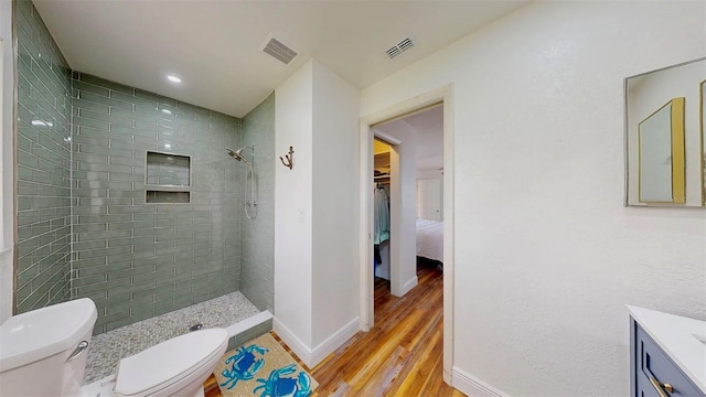 full bathroom featuring visible vents, toilet, vanity, and tiled shower