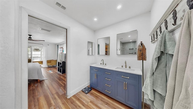 ensuite bathroom with a ceiling fan, wood finished floors, visible vents, a sink, and ensuite bathroom