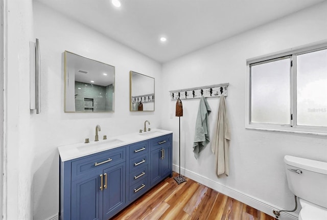 bathroom with a sink, toilet, wood finished floors, and double vanity