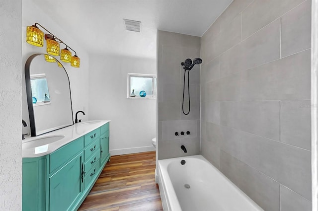 full bathroom featuring double vanity, visible vents, wood finished floors, and a sink