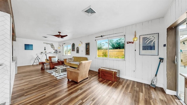 living room featuring visible vents, baseboards, wood finished floors, and a ceiling fan