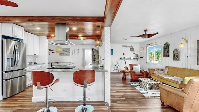 kitchen featuring open floor plan, island exhaust hood, wood finished floors, stainless steel fridge, and a ceiling fan