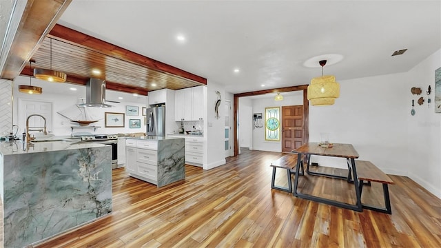 kitchen featuring light wood finished floors, a sink, appliances with stainless steel finishes, white cabinetry, and exhaust hood