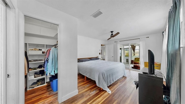 bedroom featuring ceiling fan, visible vents, attic access, and wood finished floors