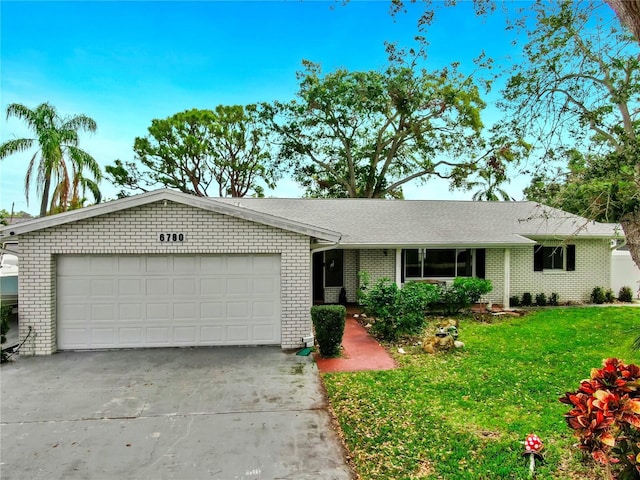 ranch-style home featuring brick siding, a shingled roof, a front lawn, a garage, and driveway