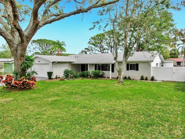 exterior space with a gate, fence, a front lawn, a garage, and brick siding