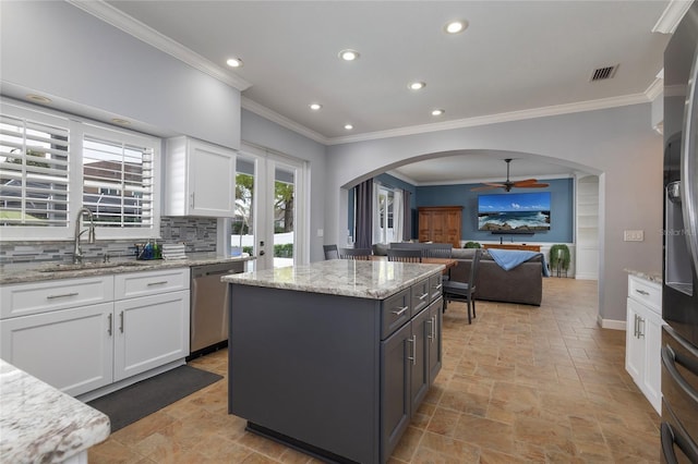 kitchen with a sink, a center island, white cabinetry, arched walkways, and dishwasher